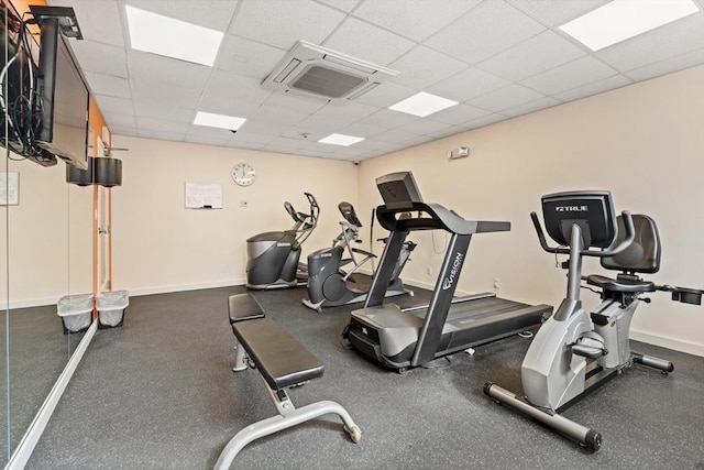 workout area featuring baseboards and a paneled ceiling