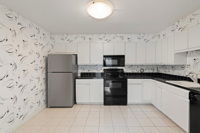 kitchen with dark countertops, black appliances, wallpapered walls, white cabinetry, and a sink