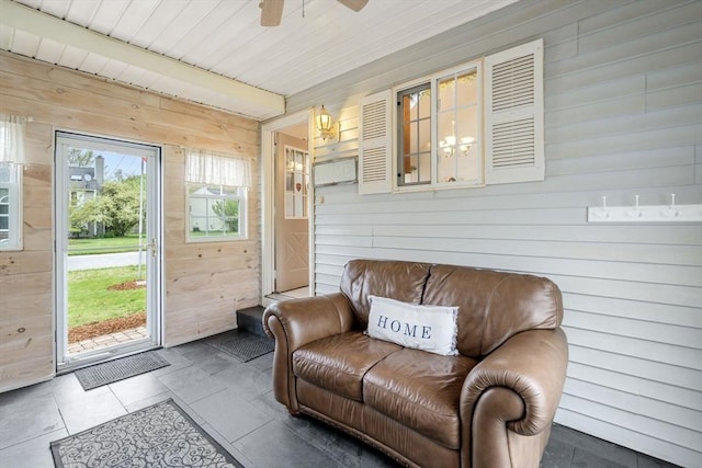 sitting room with wood walls and ceiling fan