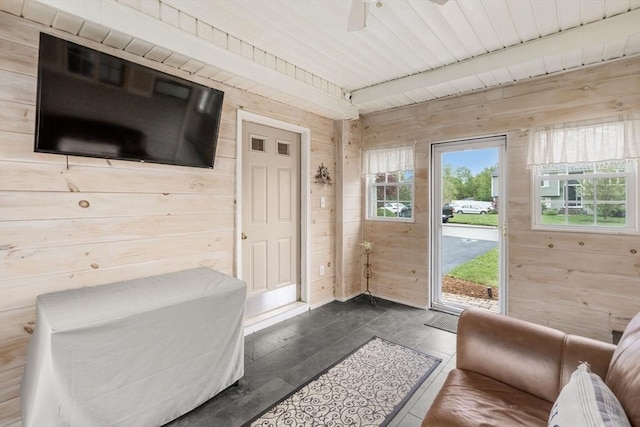 entryway with wooden walls, a ceiling fan, baseboards, and wooden ceiling
