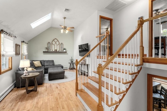 stairs with ceiling fan, baseboard heating, hardwood / wood-style floors, a skylight, and a baseboard radiator
