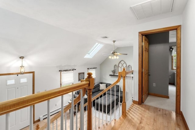corridor featuring light wood-type flooring, a skylight, baseboards, and lofted ceiling