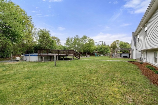 view of green lawn with a wooden deck, an outdoor pool, and a playground