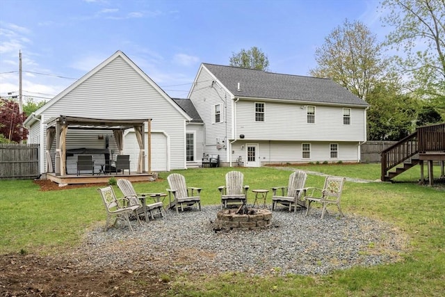 rear view of property with a fire pit, a deck, stairs, roof with shingles, and a hot tub