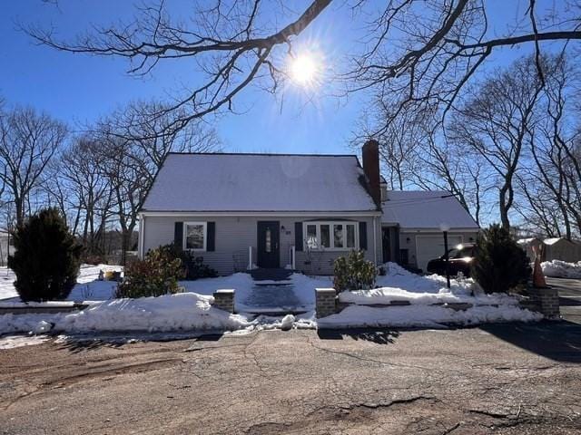 new england style home featuring a garage and a chimney