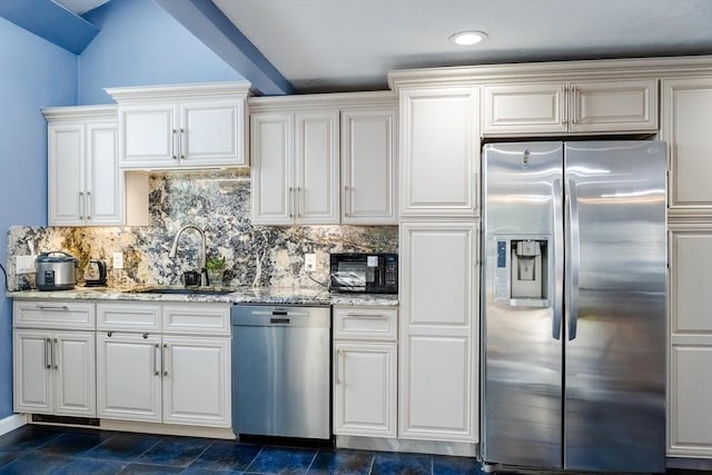 kitchen featuring decorative backsplash, light stone countertops, stainless steel appliances, white cabinetry, and a sink