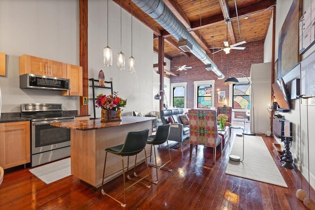 49 Munroe St Unit 405, Lynn, MA 01901 - kitchen featuring appliances with stainless steel finishes, a towering ceiling, brick wall, a ceiling fan, and a wooden ceiling with exposed beams