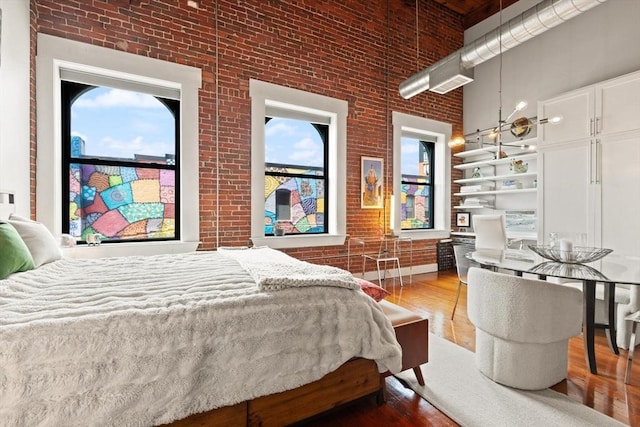 49 Munroe St Unit 405, Lynn, MA 01901 - bedroom with a high ceiling, brick wall, wood finished floors, and multiple windows