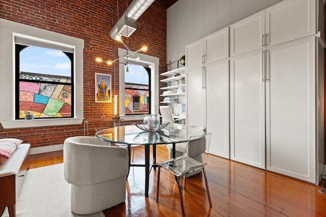 49 Munroe St Unit 405, Lynn, MA 01901 - dining space featuring brick wall, wood-type flooring, and a towering ceiling