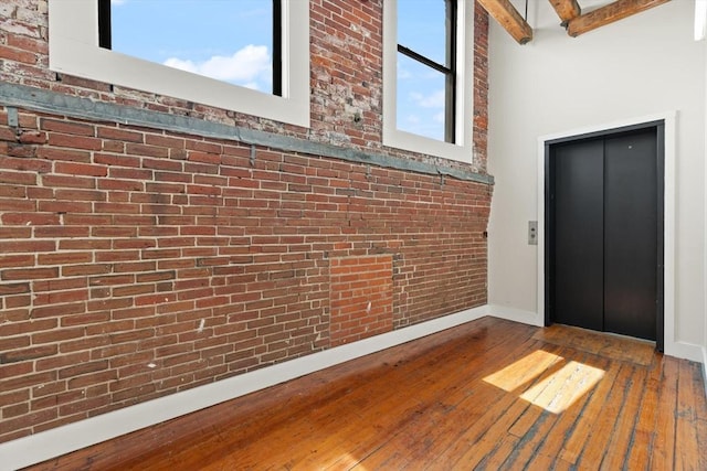49 Munroe St Unit 405, Lynn, MA 01901 - entryway with elevator, brick wall, hardwood / wood-style flooring, beamed ceiling, and a high ceiling