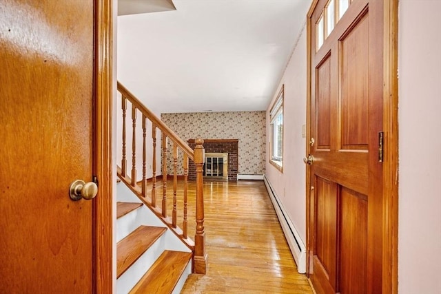 49 Whitman St, Weymouth, MA 02189 - entrance foyer with wallpapered walls, a baseboard radiator, a brick fireplace, light wood finished floors, and stairs