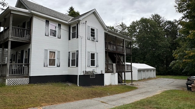 view of home's exterior featuring a lawn, an outbuilding, a balcony, and a garage