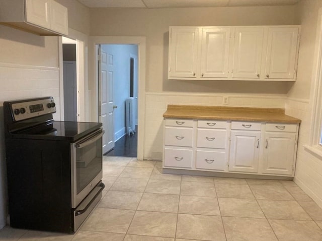 kitchen featuring electric stove, white cabinetry, and light tile patterned flooring