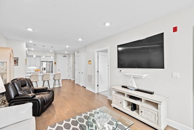 living area featuring recessed lighting, light wood-type flooring, and baseboards