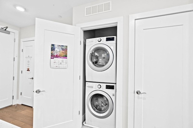 washroom with stacked washing machine and dryer and wood finished floors