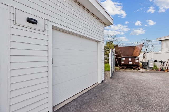 garage with asphalt driveway and fence