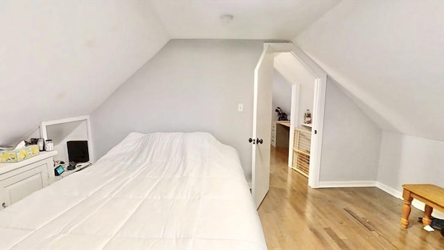 bedroom with light wood-style flooring and lofted ceiling