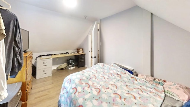 bedroom with vaulted ceiling and light wood-type flooring