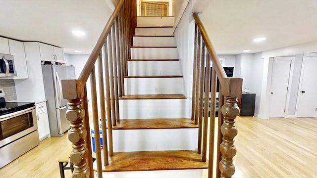 stairway featuring wood finished floors and recessed lighting
