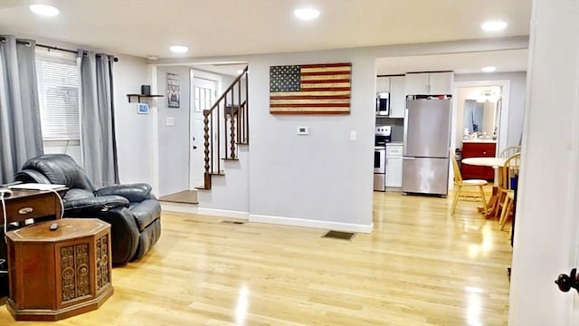 living area featuring light wood-style floors, baseboards, stairway, and recessed lighting