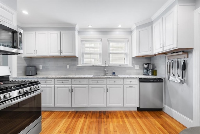 72 Edgecliff Rd Unit 72, Watertown, MA 02472 - kitchen with appliances with stainless steel finishes, a sink, white cabinets, tasteful backsplash, and light wood-type flooring