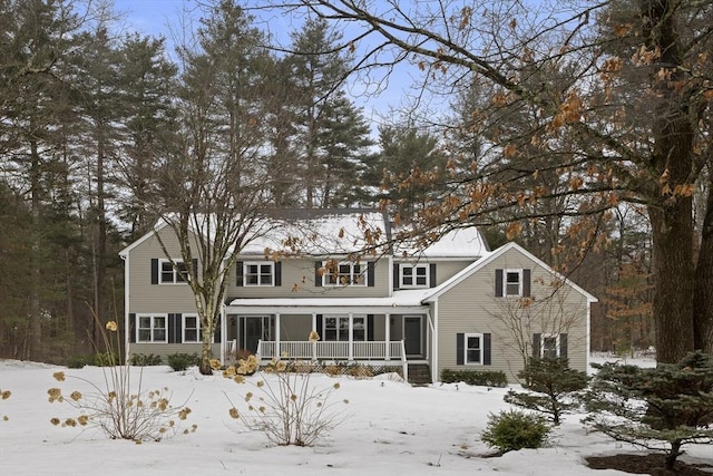 snow covered back of property with a porch