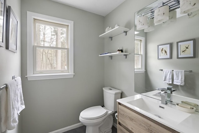 bathroom with a wealth of natural light, baseboards, vanity, and toilet