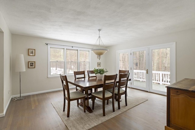 dining area featuring baseboards, french doors, a textured ceiling, and light wood-style floors