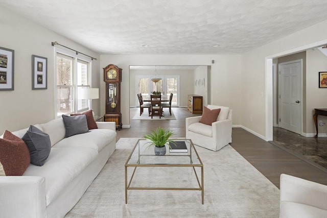 living room with plenty of natural light, a textured ceiling, baseboards, and wood finished floors