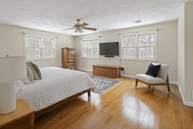 bedroom with ceiling fan, wood-type flooring, visible vents, and baseboards