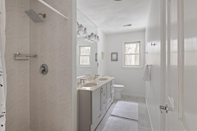 bathroom featuring visible vents, a sink, and a tile shower