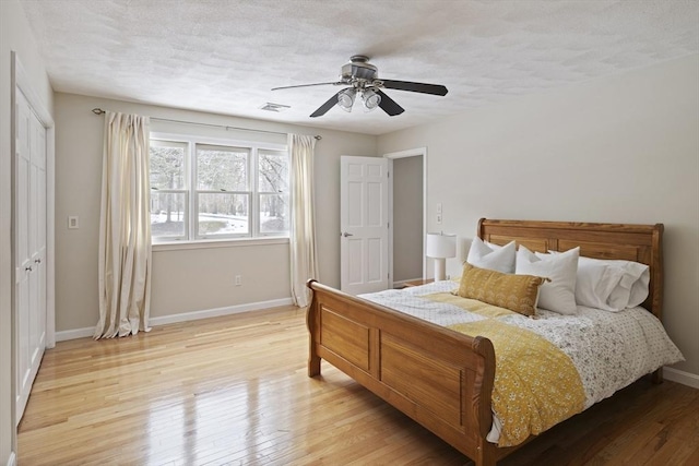 bedroom featuring a textured ceiling, light wood finished floors, and baseboards