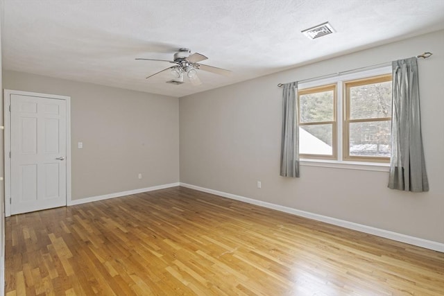 unfurnished room featuring ceiling fan, light wood finished floors, visible vents, and baseboards