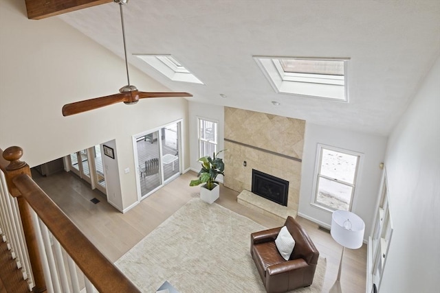 living area with vaulted ceiling with skylight, a healthy amount of sunlight, and a tiled fireplace