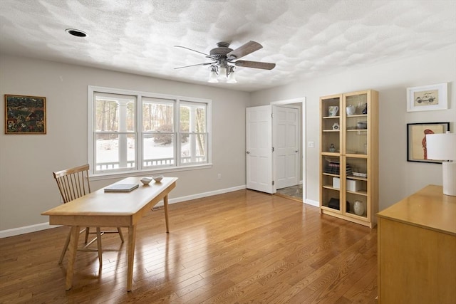 office space featuring ceiling fan, a textured ceiling, baseboards, and wood finished floors