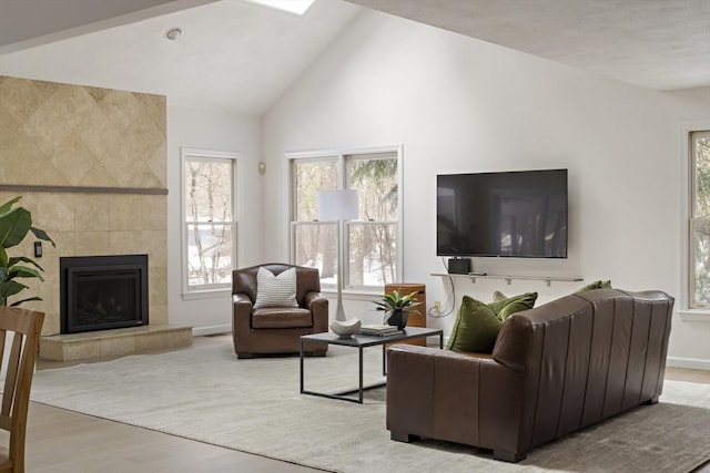 living room with lofted ceiling, a fireplace, baseboards, and wood finished floors