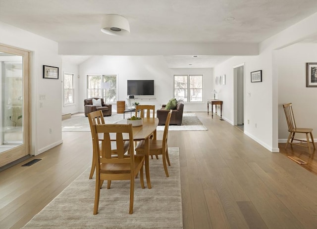 dining area featuring light wood finished floors, visible vents, and baseboards