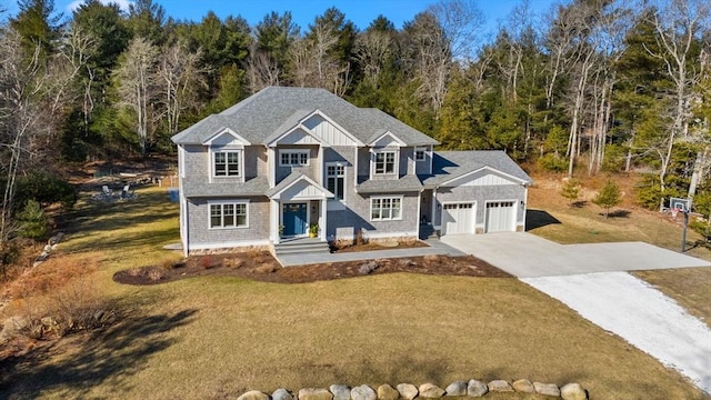 view of front of house featuring a forest view, board and batten siding, concrete driveway, a front yard, and a garage