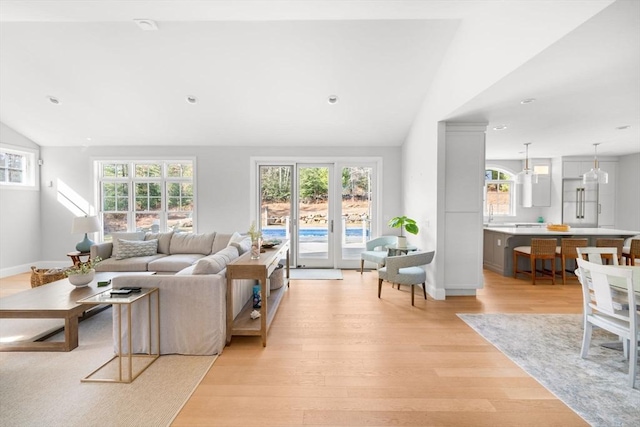 living area featuring recessed lighting, a healthy amount of sunlight, light wood-style flooring, and vaulted ceiling