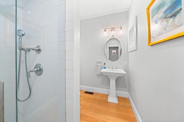 bathroom with visible vents, tiled shower, baseboards, and wood finished floors