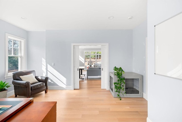 living area with light wood-style flooring, a healthy amount of sunlight, and baseboards