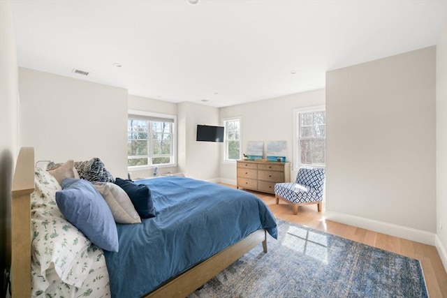 bedroom featuring visible vents, baseboards, and wood finished floors