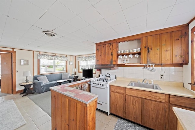 14 Mcarthur Ln, Marshfield, MA 02050 - kitchen featuring white range with gas stovetop, under cabinet range hood, a sink, light tile patterned floors, and brown cabinets