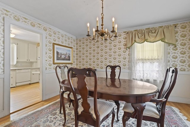 dining space featuring crown molding, light wood-type flooring, and a chandelier