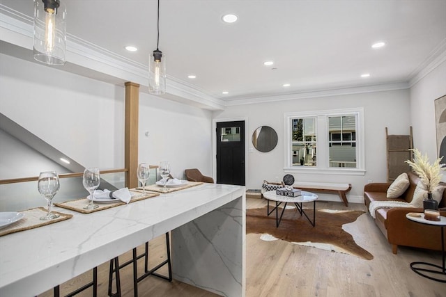 interior space with pendant lighting, ornamental molding, and light hardwood / wood-style flooring