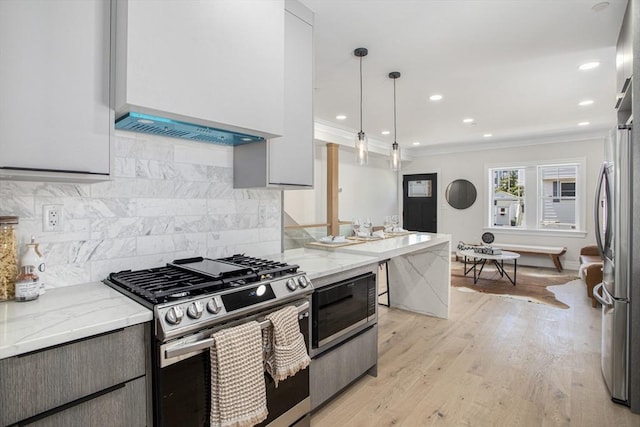 kitchen featuring decorative light fixtures, light stone counters, backsplash, and appliances with stainless steel finishes