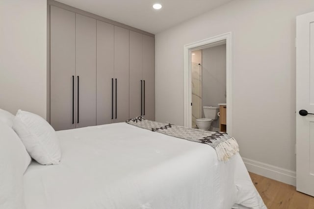 bedroom with light hardwood / wood-style flooring and ensuite bath