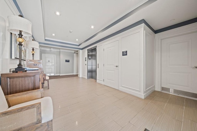 corridor with elevator and a raised ceiling