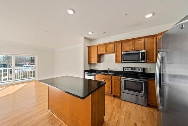 kitchen featuring stainless steel appliances, a kitchen island, crown molding, light hardwood / wood-style flooring, and sink