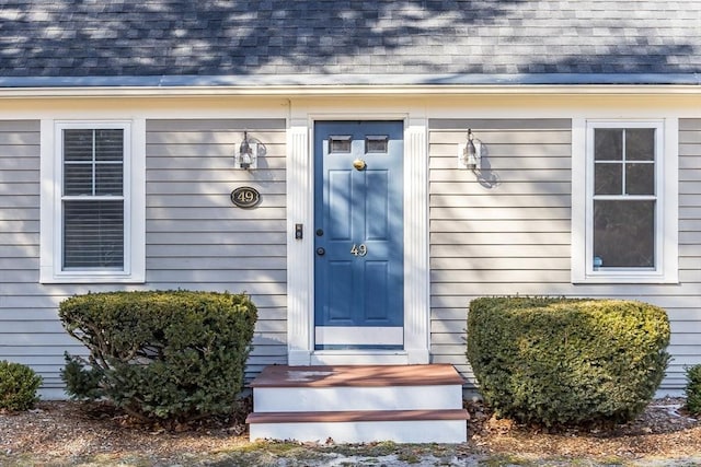 doorway to property with a shingled roof